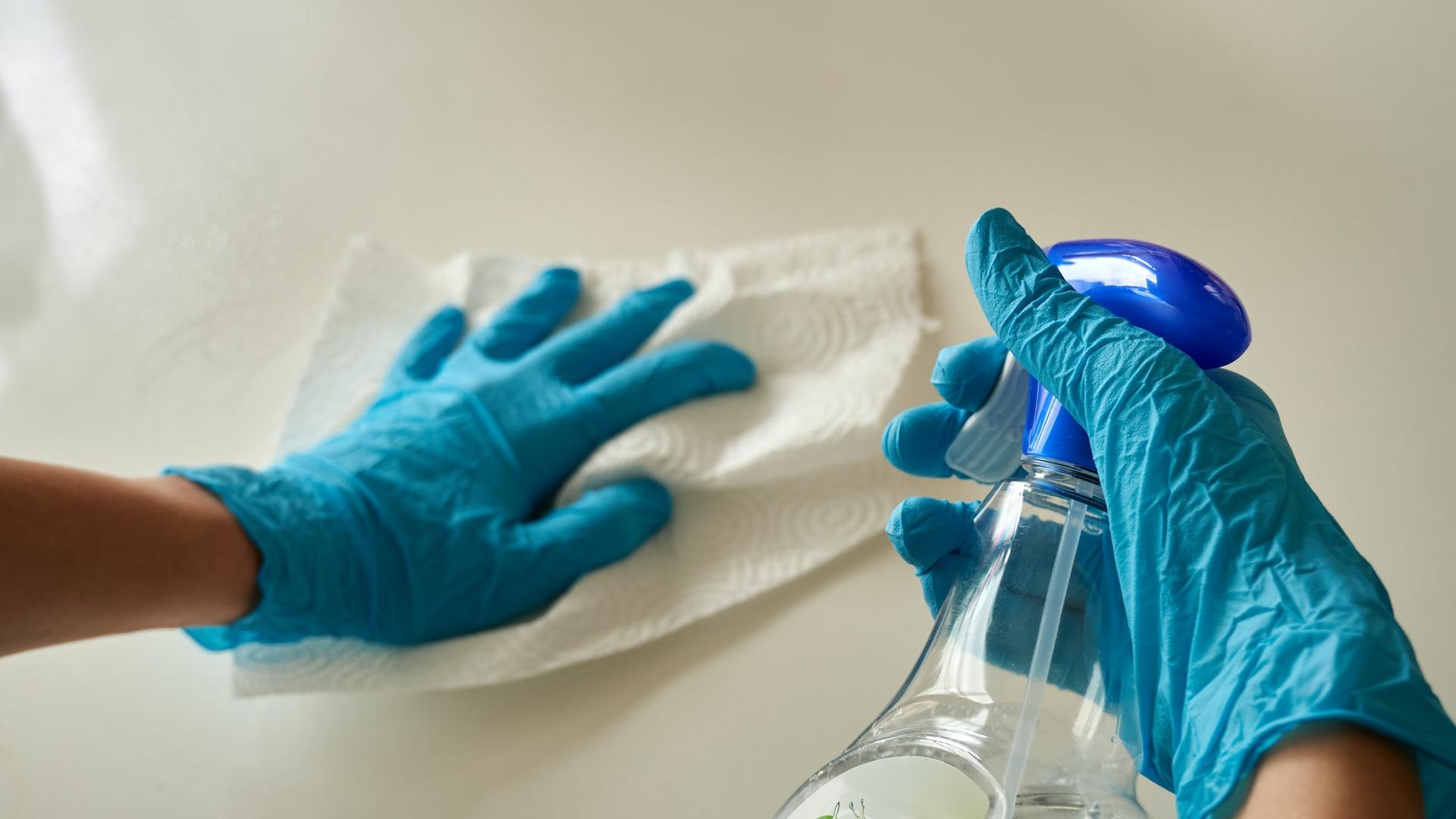 person holding blue textile near clear glass bottle